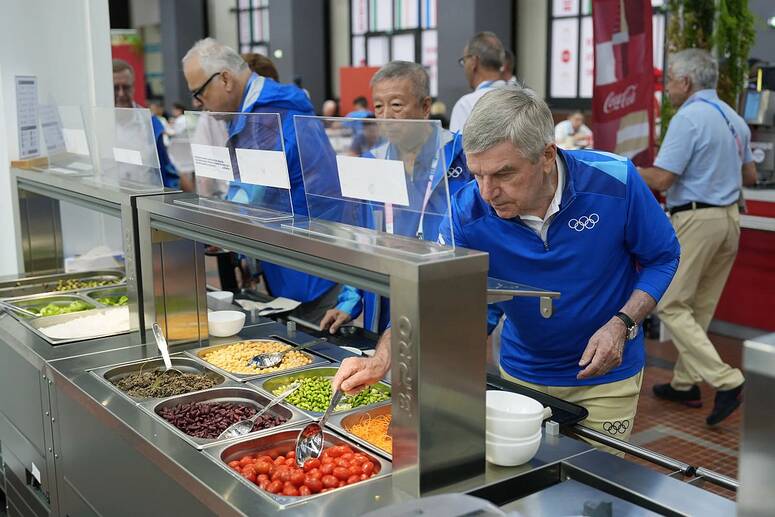 IOC president Thomas Bach tries food at the Olympic Village in Paris but athletes have been disgruntled at some of the produce on offer. Photograph: David Goldman/AFP/Getty Images